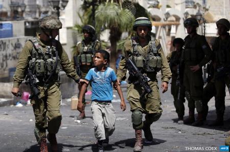 Israeli soldiers arrest a young Palestinian boy following clashes in Hebron, on June 20, 2014